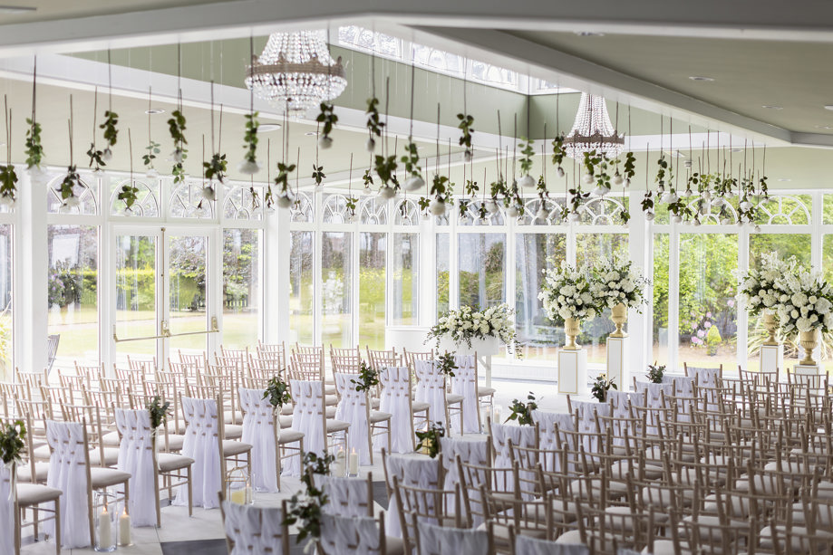 Wedding ceremony room with many windows, natural light and floral decor